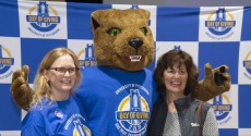 Panther mascot Roc standing between two women