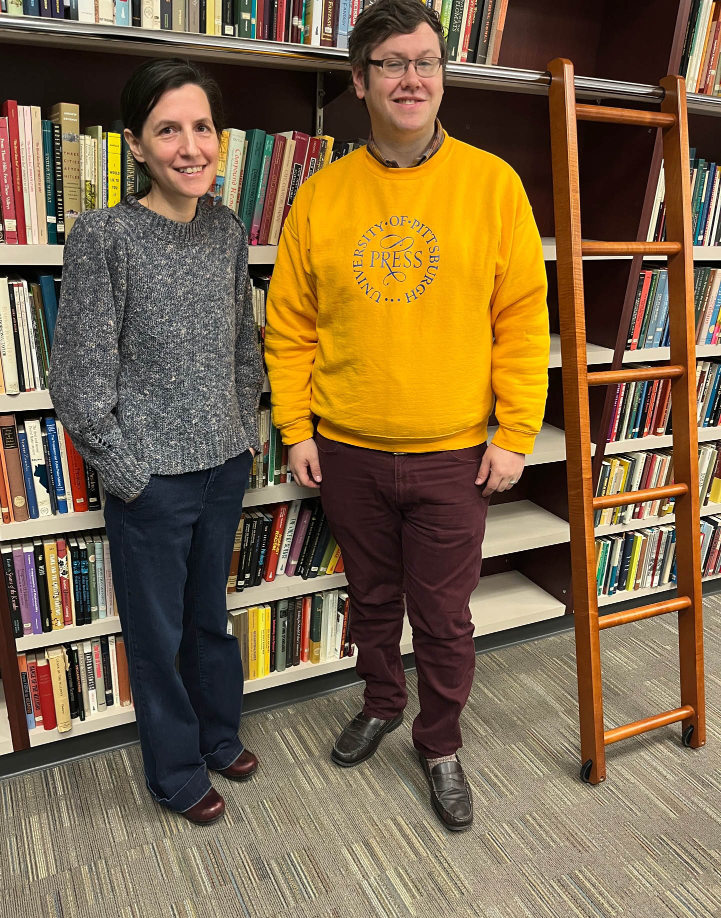 Two people standing in front of bookshelves
