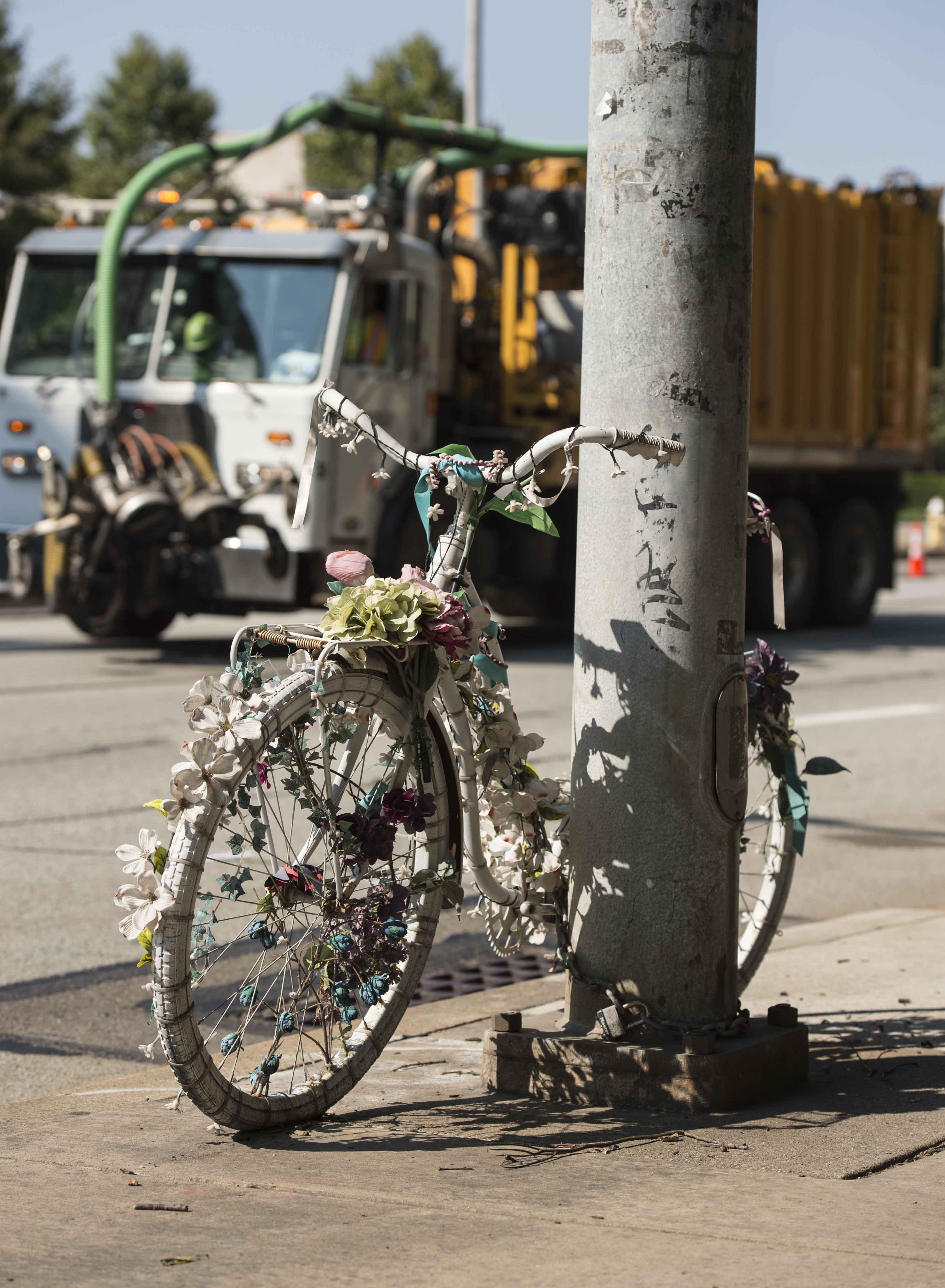 White bike adorned with flowers ties to pole