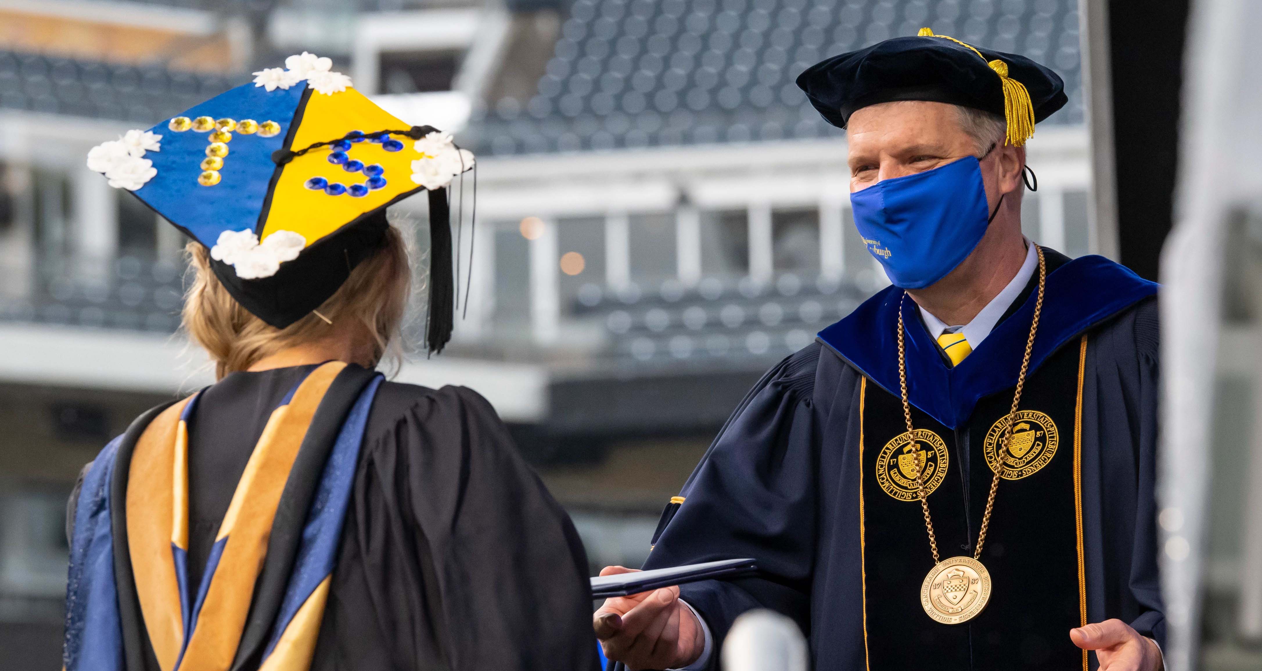 Chancellor with mask handing out diploma