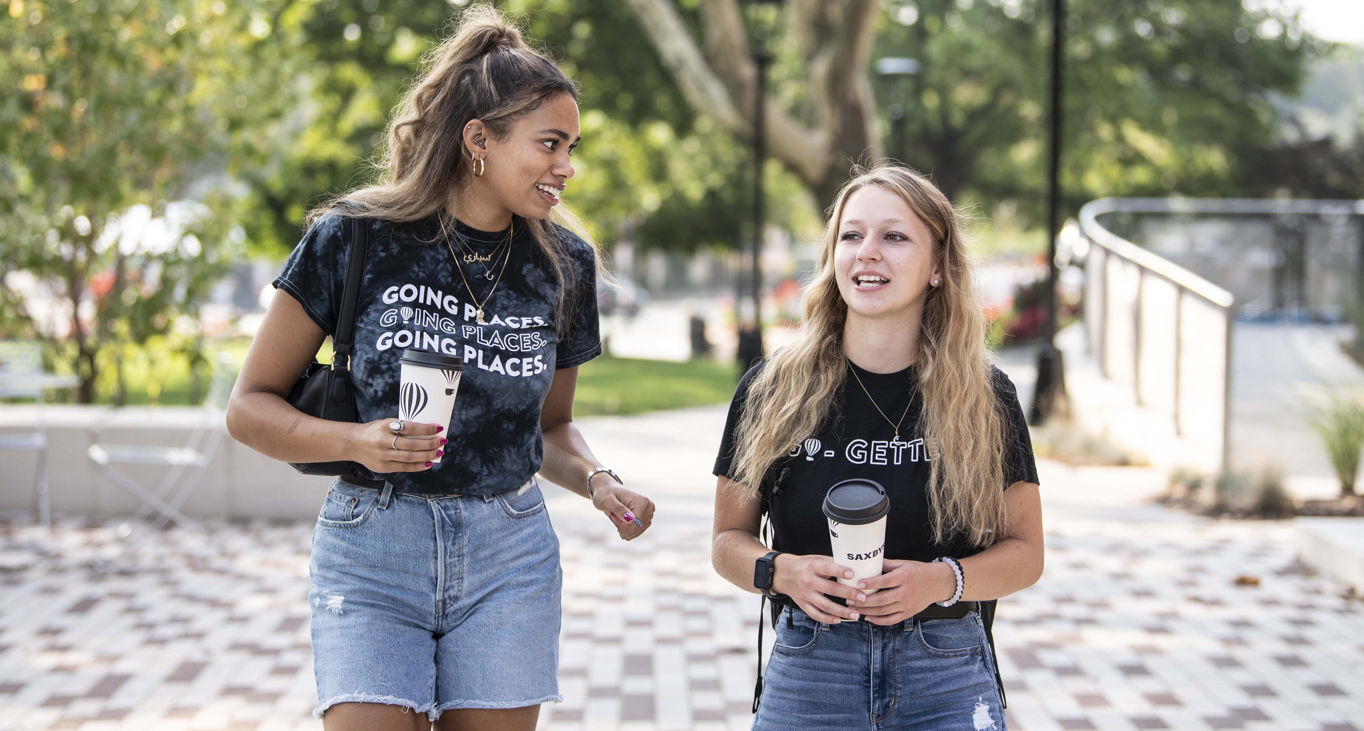 Students Ceari Robinson and Angel Albright-Sexton walking with coffee cups