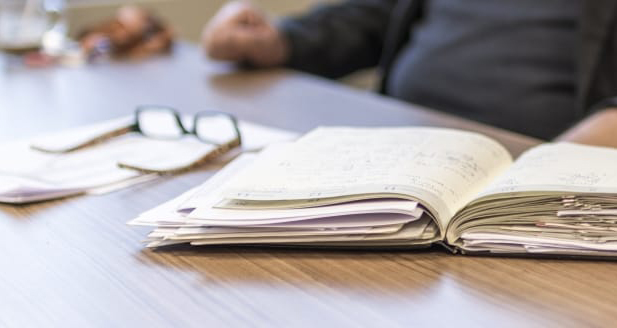 Book and glasses on desk in front of person