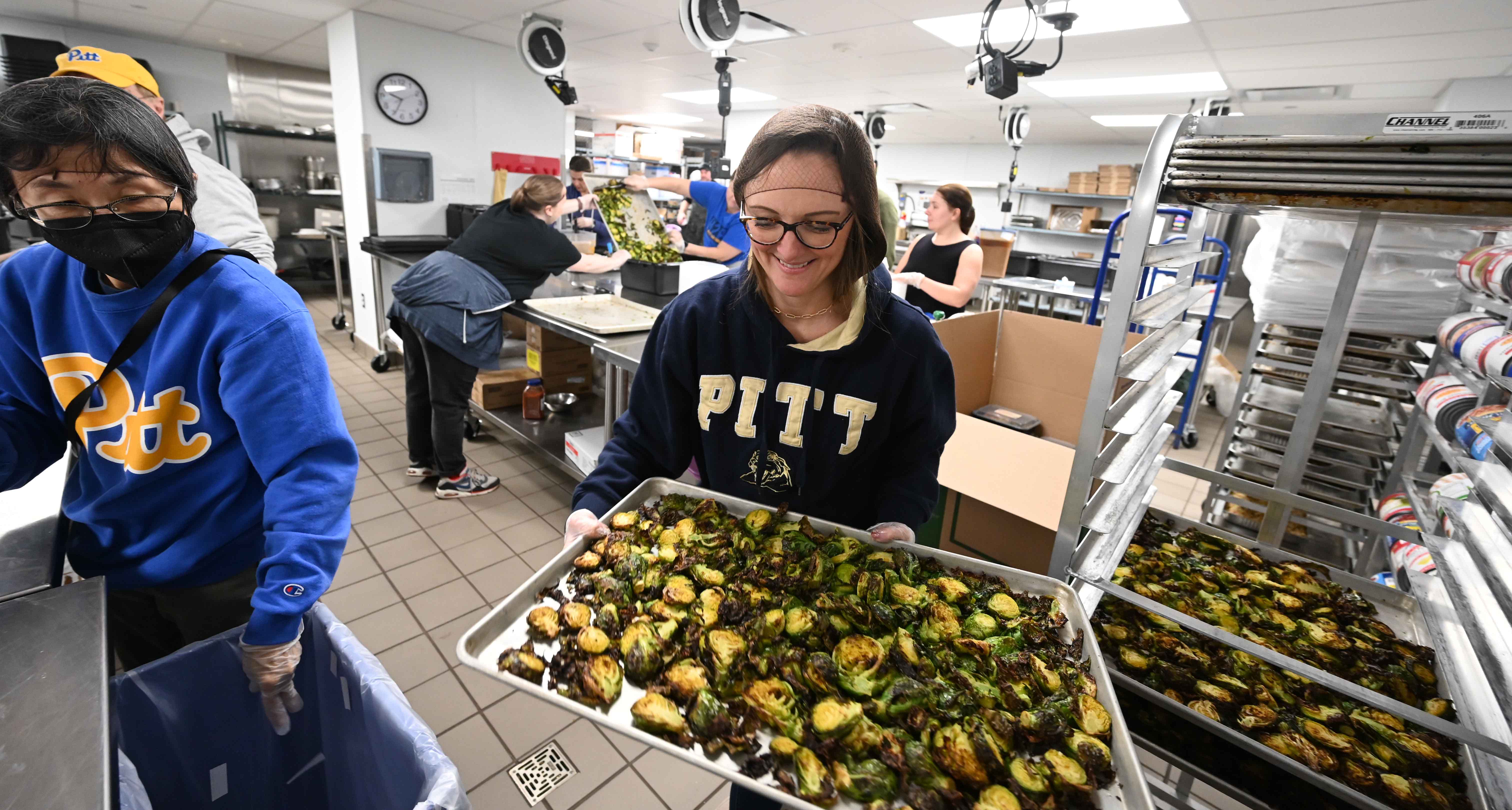 Volunteers pack meal kits in 2023 in The Eatery kitchen in Litchfield Towers that were distributed to community members during the annual Christmas Day at Pitt event. (Aimee Obidzinski | University of Pittsburgh) People preparing food
