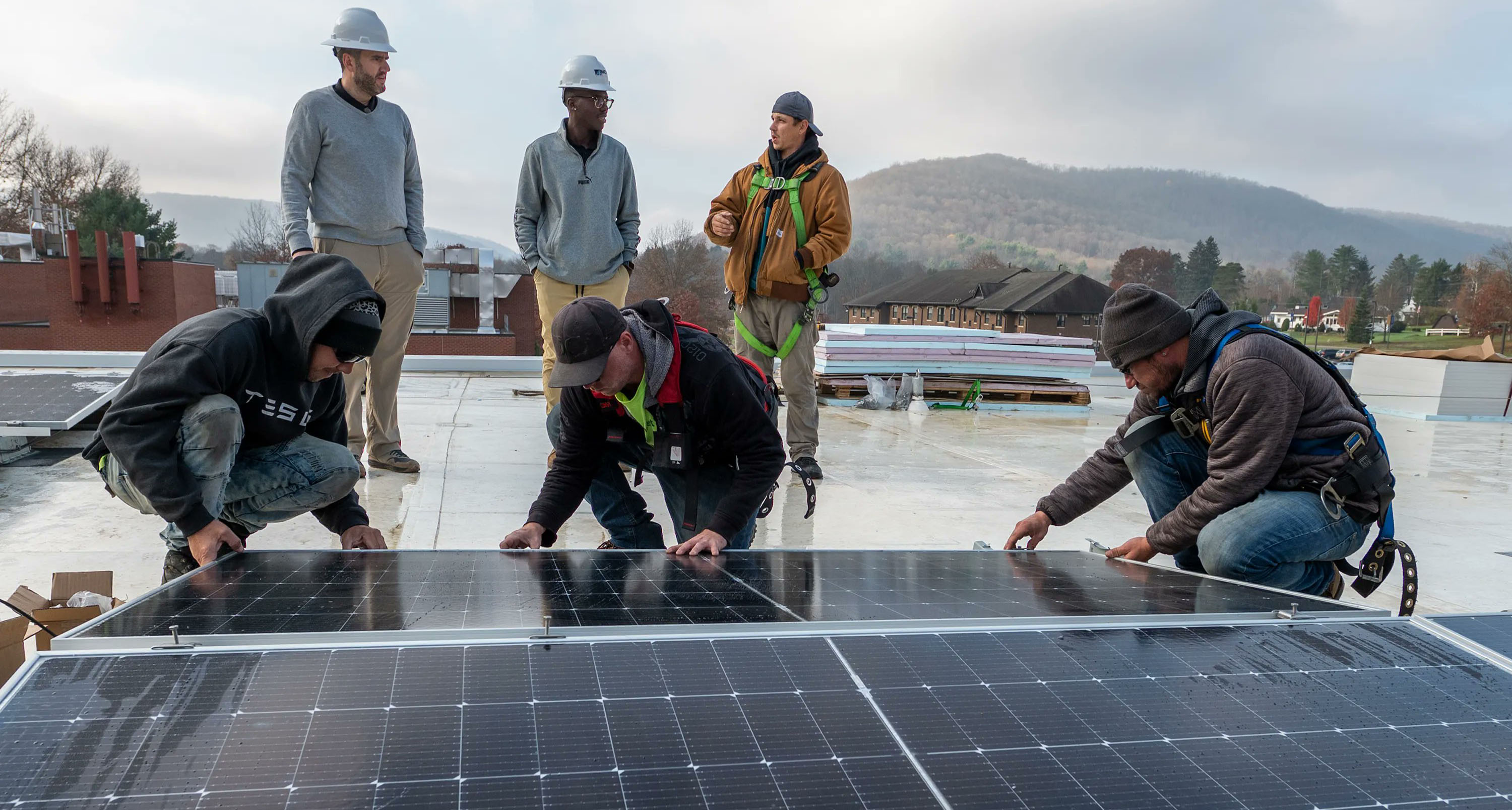 Men installing solar panels as others look on