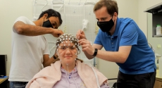 Person with electrodes on head with two others around her.