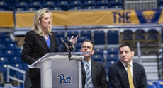 Heather Lyke speaking with volleyball and wrestling coaches looking on