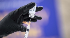 Hand holding vial of vaccine and needle