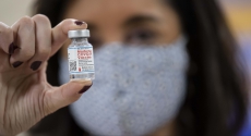 A woman holds up a container of COVID-19 vaccine